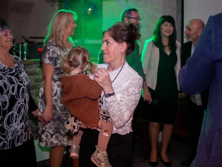 Babička tancující s malou vnučkou v náručí na oslavě narozenin