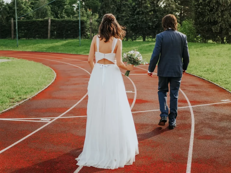 netradiční svatební fotografie ženicha a nevěsty na atletickém oválu