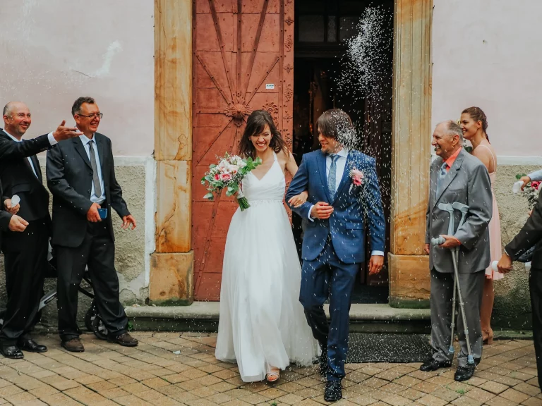 Focení svatby - novomanželé vycházejí z kostela a hosté na ně hážou rýži.